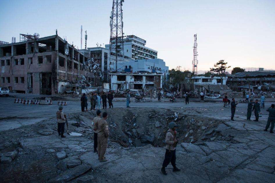 Afghan security personnel and residents stand near the crater left by a truck bomb attack in Kabul, May 31, 2017.