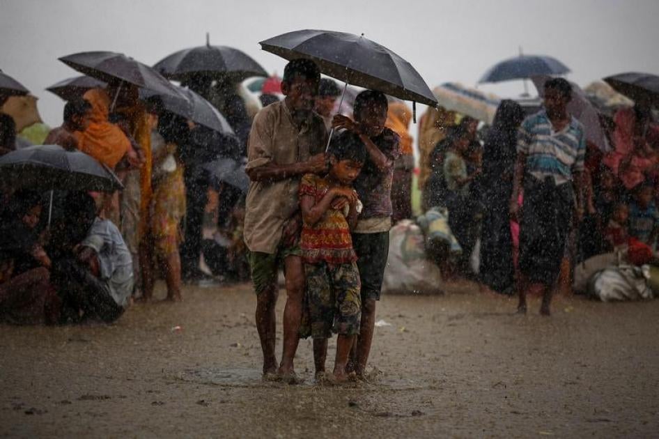 Rohingya refugees try to take shelter from torrential rain as they are held by the Border Guard Bangladesh (BGB) after illegally crossing the border, in Teknaf, Bangladesh, August 31, 2017.