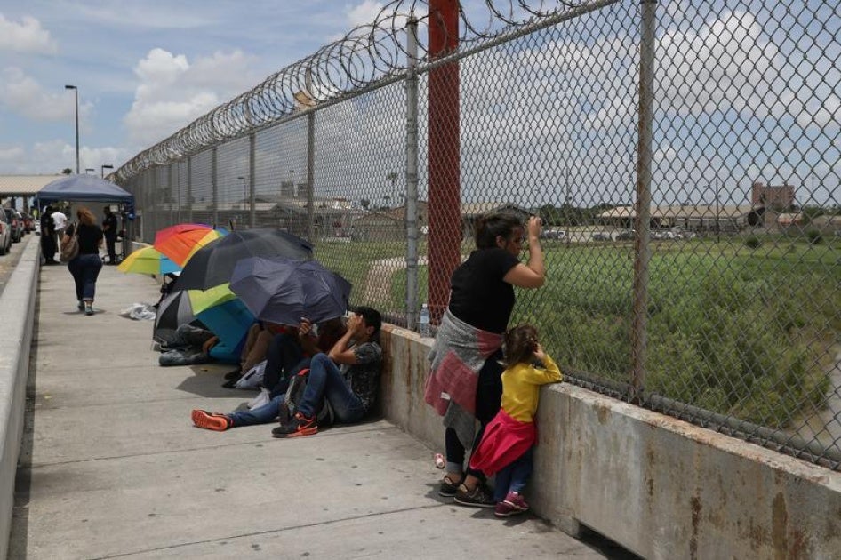 A Honduran mother and her 3-year-old daughter wait with fellow asylum seekers on the Mexican side of the Brownsville-Matamoros International Bridge after being denied entry by U.S. Customs and Border Protection officers near Brownsville, Texas, U.S., June