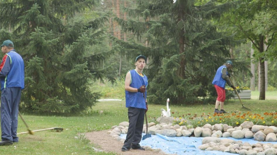 A young man does yard work on the grounds of a closed state institution for adults with disabilities.