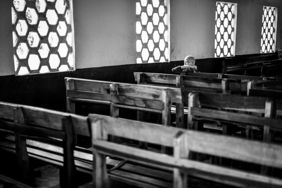 A girls with albinism seats on a bench in a church