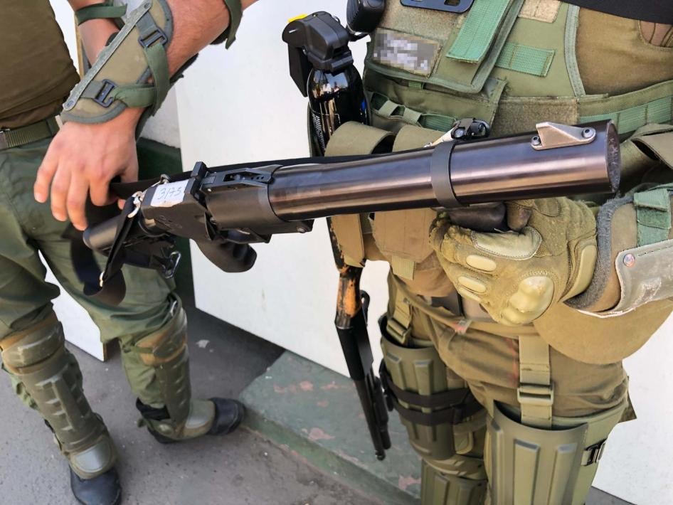 Um membro da polícia segura uma arma de gás lacrimogêneo. 