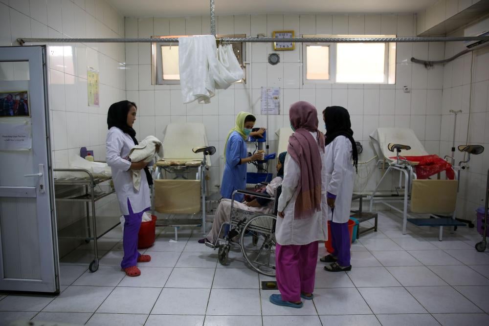 Midwives care for a mother who has just given birth in a hospital room