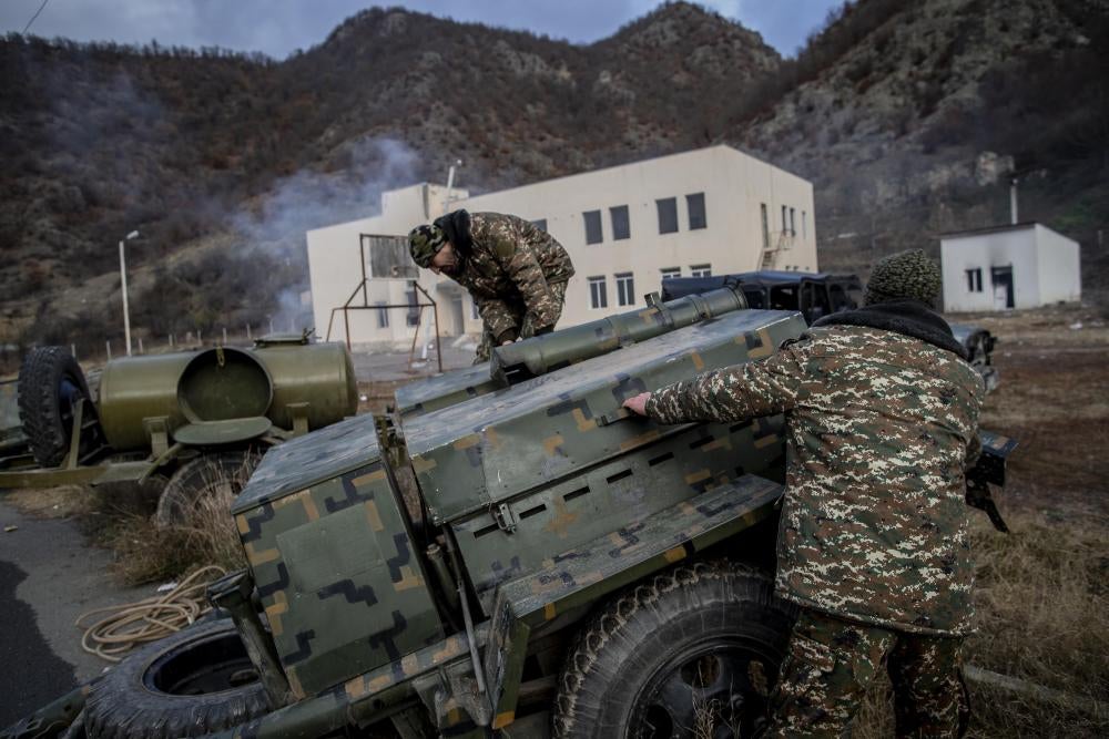Soldiers with equipment in front of a school building with smoke rising from the top