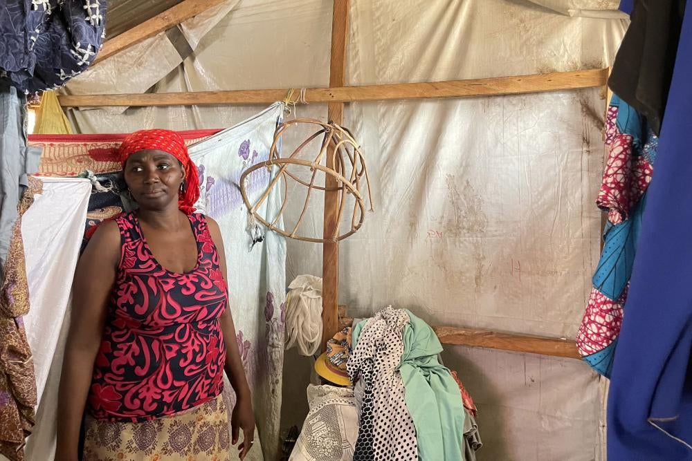 A woman stands inside a tent