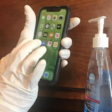 A woman in medical gloves holding an iPhone.