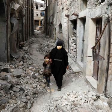 A woman in a black niqab and face mask walks through a deserted street with a child