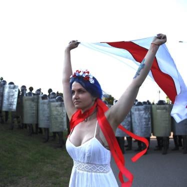 A woman carries a white-red-white flag as law enforcement officers block the street during an opposition rally against presidential election results in Minsk, Belarus.