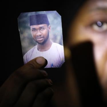 A woman holds up a phone with a photo of her husband on it