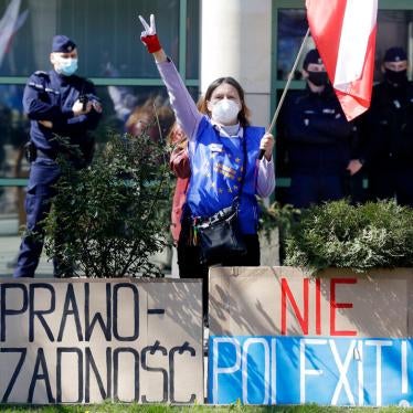 A pro-EU protestor stands outside the Constitutional Tribunal in Warsaw, Poland, on April 28, 2021 with posters that say Rule of Law and No Polexit! 