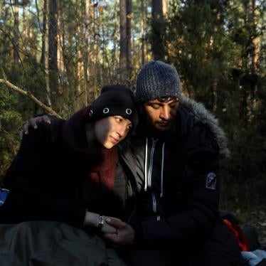 Sara, 26, and Hassan, 24, both from Syria, sit on the ground in the forest in Lewosze, Poland, after crossing the border from Belarus, October 29, 2021.