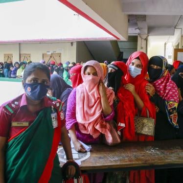 Women in protective face masks stand in a long line