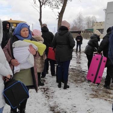 People hold their belongings as they wait to get into a van