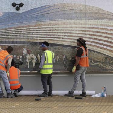 Workers in front of a mural of a stadium 
