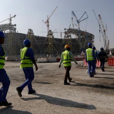 Workers walk toward a sports stadium under construction