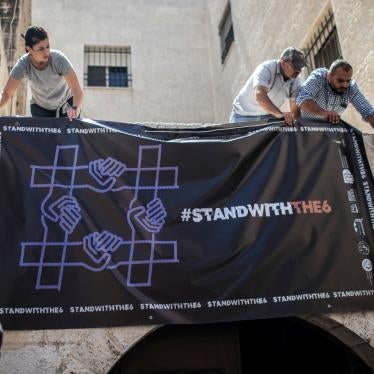 Activists hang a poster outside a Palestinian civil society organization