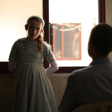  شهد، فتاة عمرها 12 عاما ولديها إعاقة سمعية، تقف أمام نافذة تواجه والدها، في المنزل الذي تعيش فيه عائلتها في أعزاز، حلب، سوريا. 7 يونيو/حزيران 2022.