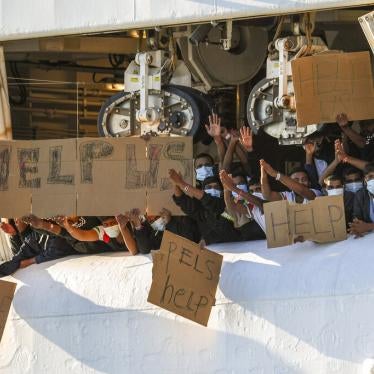 Migrants hold banners asking for help from a deck of the Geo Barents rescue ship operated by Doctors Without Borders, in Catania's port, Sicily, southern Italy, November 7, 2022