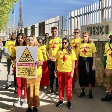 Campaigners and waste pickers from around the world holding a sign reading, “plastic puts 218 million people at risk of more severe flooding,” outside the UNESCO Headquarters in Paris, where the second round of plastics treaty negotiations took place, May 30, 2023.