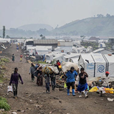 Group walks through camp of tents.