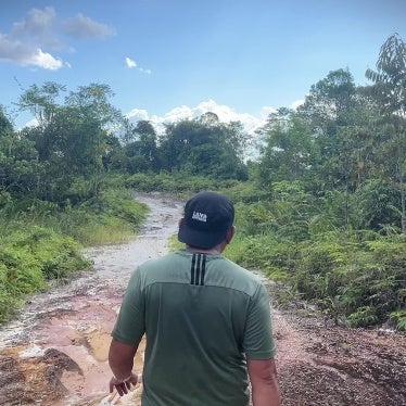 A man walks down a path through a rainforest 