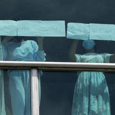 Migrants expelled from the US hold up papers that read “We are not safe in our country” in the window of a hotel