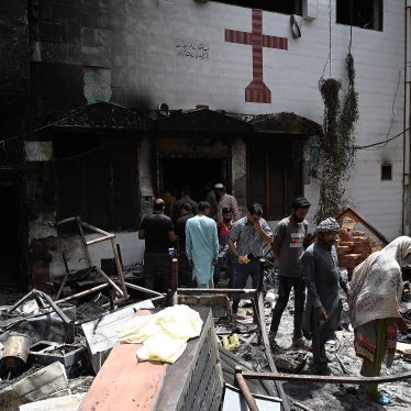 Police and residents stand amid debris outside the torched St. John Church