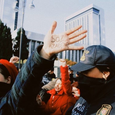 A woman wearing a face mask holds her hand up at a protest