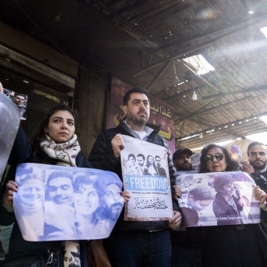 People hold photos and protest signs at a demonstration