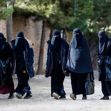 Afghan niqab-clad women walk along a street on the outskirts of Kabul.