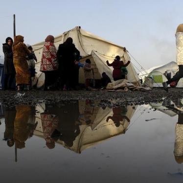 Stranded refugees and migrants walk inside a relocation camp as they wait to cross the Greek-Macedonian border, near the Greek village of Idomeni, March 1, 2016.