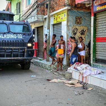 Um veículo blindado da polícia militar passa ao lado de uma pessoa morta pela polícia, em 7 de abril de 2016, na favela do Jacarezinho. A polícia militar matou outras duas pessoas nessa mesma operação. 