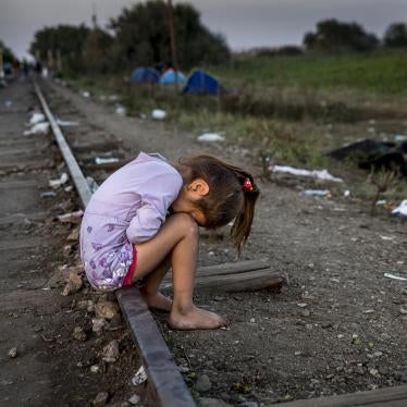 An exhausted child cries on the railway tracks between Serbia and Hungary as night falls, and her family argues nearby whether to cross into Hungary and face temporary detention.