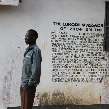 A community member in Lukodi stands next to a memorial of a May 19, 2004 massacre, one of the atrocities for which Dominic Ongwen is facing charges before the International Criminal Court. Over 4,000 victims are participating in the trial. ©2016 G. GT.