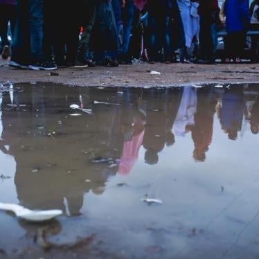 Migrants in Calais gather in the rain for a clothing distribution in an industrial zone on the outskirts of Calais, France. © Futuro Berg/Help Refugees, October 2017