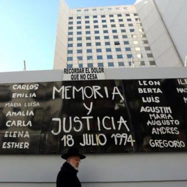 A man walks by a sign that reads "Memory and Justice" next to the names of the victims of the 1994 Argentine Israeli Mutual Association (AMIA) bombing