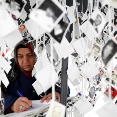 A woman writes in a book inside a traveling monument called 'Prijedor 92' outside the Yugoslav War Crimes Tribunal (ICTY)