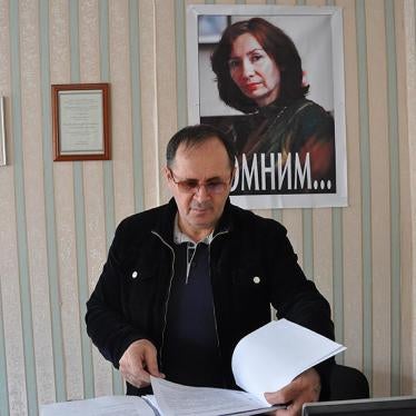 Oyub Titiev stands in front of a portrait of his murdered colleague, Natalia Estemirova, in Memorial's Grozny office.