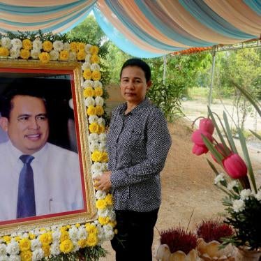 Kem Thavy stands by a portrait of her brother Kem Ley at his grave in Ang Takok, Cambodia, November 20, 2016. © 2016 AP Photo/Denis Gray