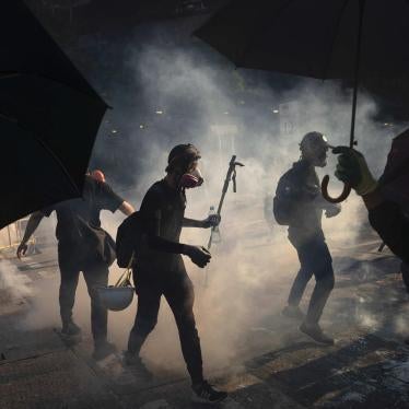 Protestors stand surrounded by smoke from tear gas shells in Hong Kong, October 1, 2019.