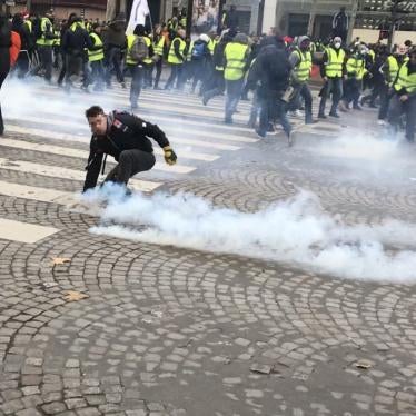Protester picks up a tear gas grenade during a police charge on December 8, 2019 on the Champs Elysees, Paris.