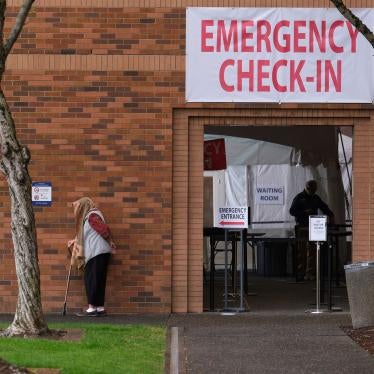 A woman waits outside the emergency check-in entrance at the Providence Medical Center in Portland, Ore., on March 24, 2020. 
