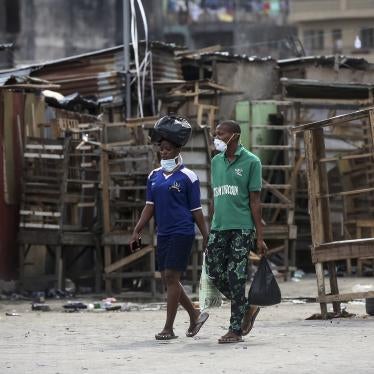 People walk past closed street stalls and shops in Lagos, Nigeria on March 26, 2020 during a government-imposed lockdown to halt the spread of COVID-19. 2020 AP Photo/Sunday Alamba.