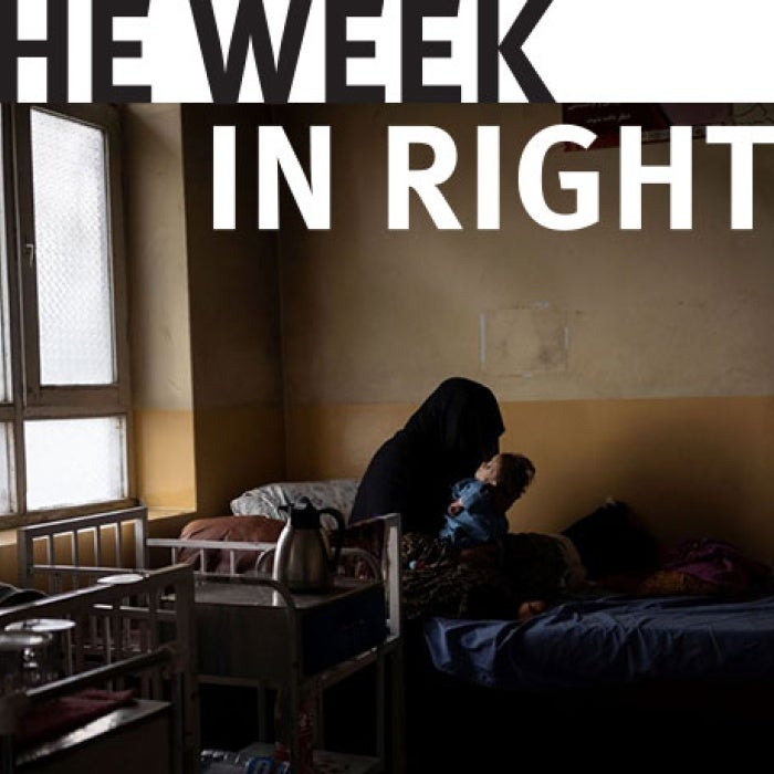 Figure holds doll while sitting on bed. 