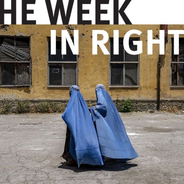 Afghan women wait to receive food rations distributed by a humanitarian aid group, in Kabul, Afghanistan